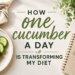 Pinterest graphic featuring fresh cucumber slices on a wooden cutting board beside a jar of cucumber water in a bright, airy kitchen. Large text reads, “The Simple Cucumber Habit That Changed How I Eat for Good.” The image promotes a personal blog post about using one small daily habit to build healthier eating habits without dieting.